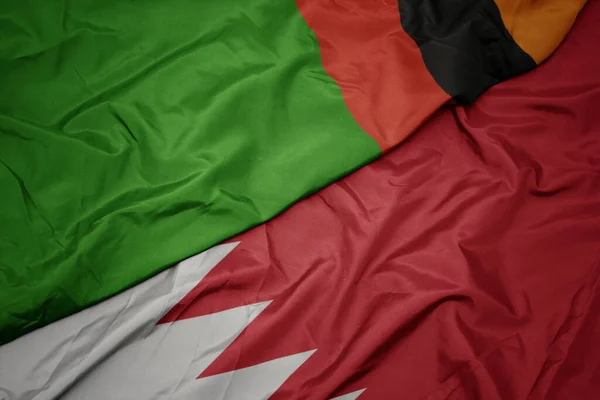 waving colorful flag of bahrain and national flag of zambia. macro