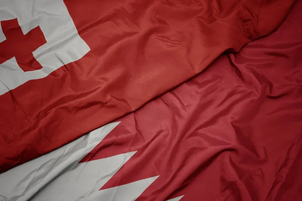 waving colorful flag of bahrain and national flag of Tonga . macro