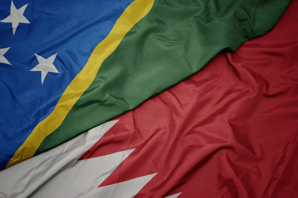 waving colorful flag of bahrain and national flag of Solomon Islands . macro