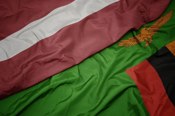 ザンビアのカラフルな旗とラトビアの国旗を振っています マクロ — ストック写真