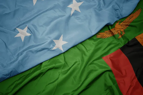 waving colorful flag of zambia and national flag of Federated States of Micronesia . macro