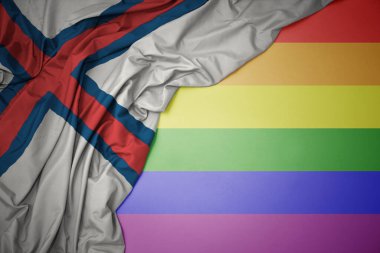 Eşcinsel gökkuşağı arka planında Faroe Adaları 'nın renkli bayrağını sallayan.