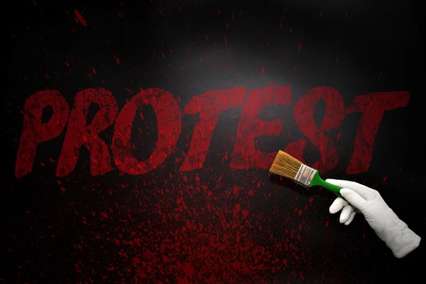 Hand in glove with the brush painting the text protest on a black surface — Stock Photo, Image