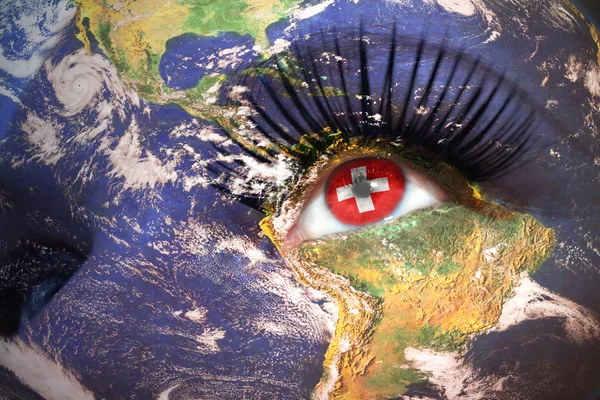 Woman's face with planet Earth texture and swiss flag inside the eye. — Stockfoto