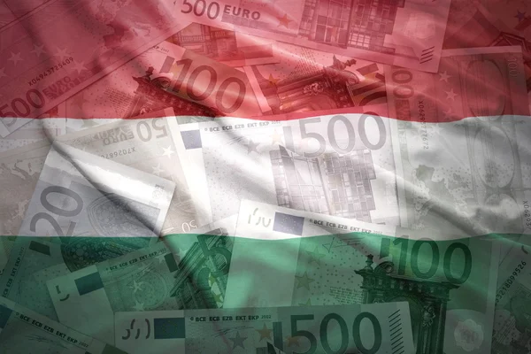 Bandera húngara ondeando colorido sobre un fondo de dinero en euros — Foto de Stock