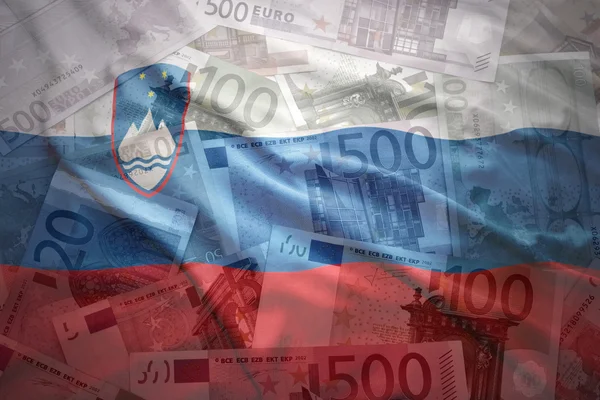 Colorful waving slovenian flag on a euro money background — Stock fotografie