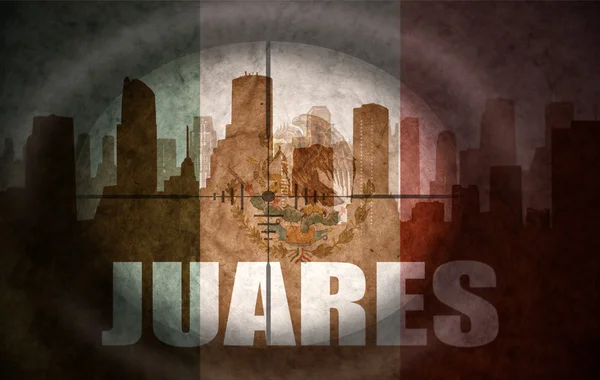 Sniper scope aimed at the abstract silhouette of the city with text Juarez at the vintage mexican flag — Stock fotografie