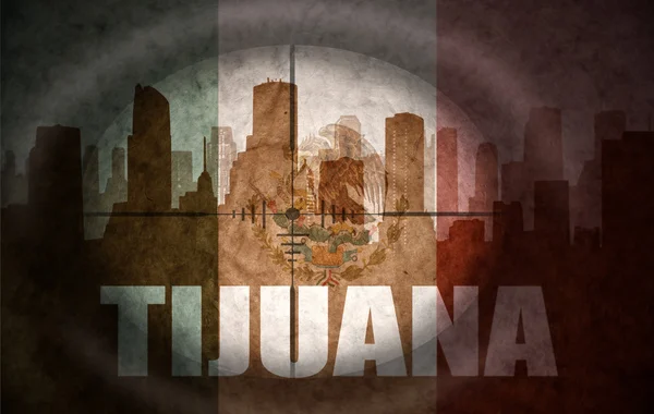 Sniper scope aimed at the abstract silhouette of the city with text Tijuana at the vintage mexican flag — Zdjęcie stockowe
