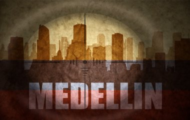 sniper scope aimed at the abstract silhouette of the city with text Medellin at the vintage colombian flag. concept