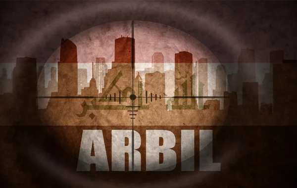 Sniper scope aimed at the abstract silhouette of the city with text Arbil at the vintage iraqi flag. concept — Stock Photo, Image