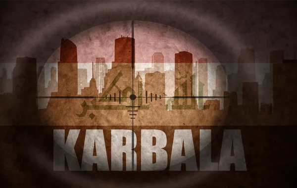 Sniper scope aimed at the abstract silhouette of the city with text Karbala at the vintage iraqi flag. concept — Stock Photo, Image