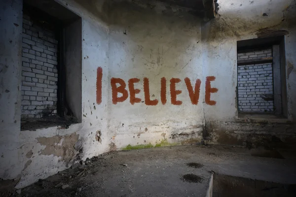 Text i believe on the dirty old wall in an abandoned ruined house — Stock Photo, Image