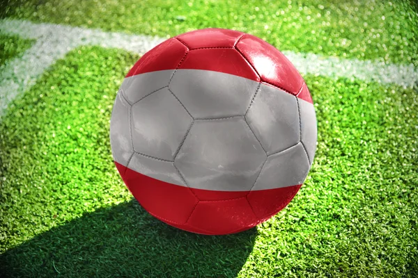 Fotbalový míč s národní vlajkou Rakouska leží na zelené louce poblíž bílá čára — Stock fotografie