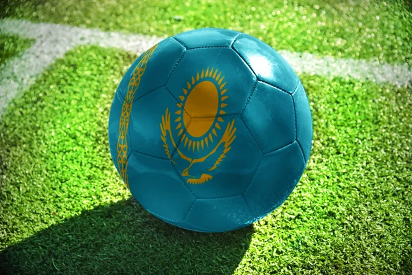 Bola de futebol com a bandeira nacional do Cazaquistão encontra-se no campo verde perto da linha branca — Fotografia de Stock