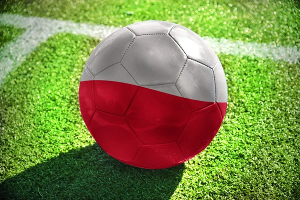 Pelota de fútbol con la bandera nacional de Polonia se encuentra en el campo verde cerca de la línea blanca —  Fotos de Stock