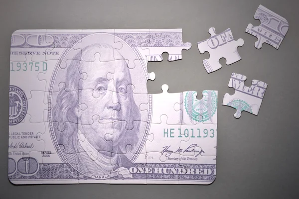 Puzzle s sto dolarů bankovku na šedém pozadí — Stock fotografie