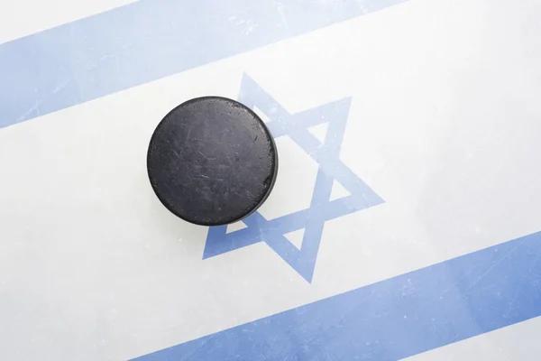 Viejo disco de hockey está en el hielo con bandera de Israel —  Fotos de Stock