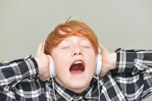 Komik kırmızı saçlı çocuk kulaklık ile — Stok fotoğraf
