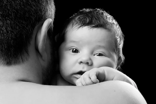 Retrato de cerca de un bebé recién nacido en el hombro de papá. Padre sosteniendo al niño sobre un fondo negro —  Fotos de Stock