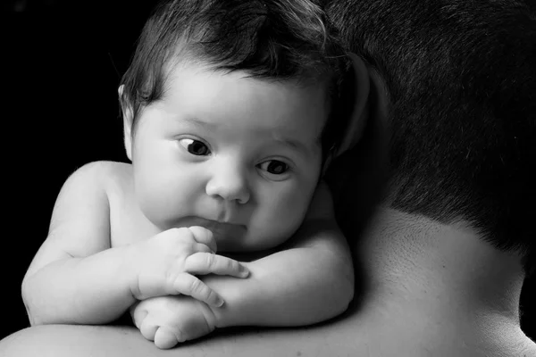 Крупным планом портрет новорожденного ребенка в плече отца. Отец держит ребенка на черном фоне — стоковое фото