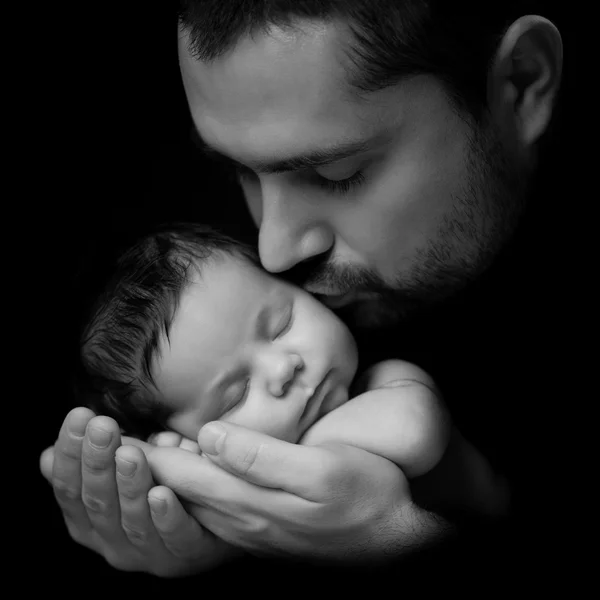 O amor do pai. Papai beija seu bebê recém-nascido. Retrato de close-up em um fundo preto — Fotografia de Stock