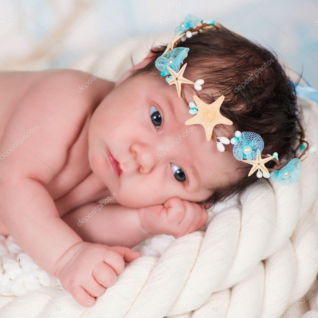 Close portrait of a sleeping newborn girl in the maritime hoop of starfish and pearls