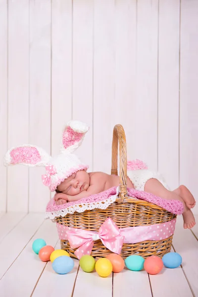 Новонароджена дівчинка в костюмі кролика має солодкі сни на плетеному кошику. Великоднє свято — стокове фото