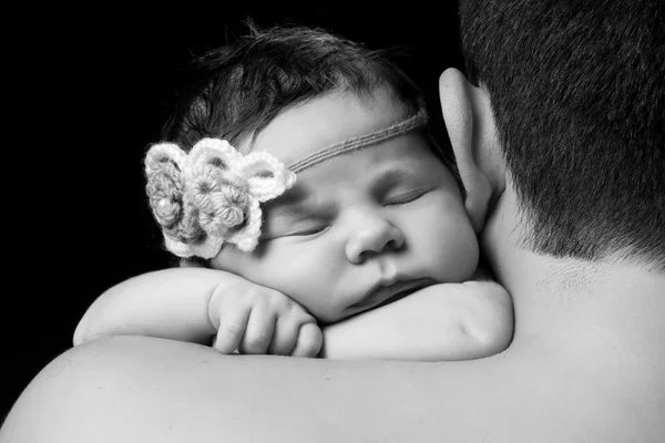 Süßes neugeborenes Mädchen mit gestricktem Stirnband, das auf Papas Schulter schläft. Studio, schwarzer Hintergrund — Stockfoto