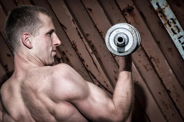 Young athletic man doing workout with heavy dumbbell — Stock Photo, Image