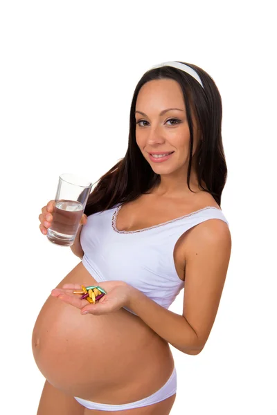 Smiling young pregnant woman taking prenatal vitamins with a glass of water — Stock Photo, Image