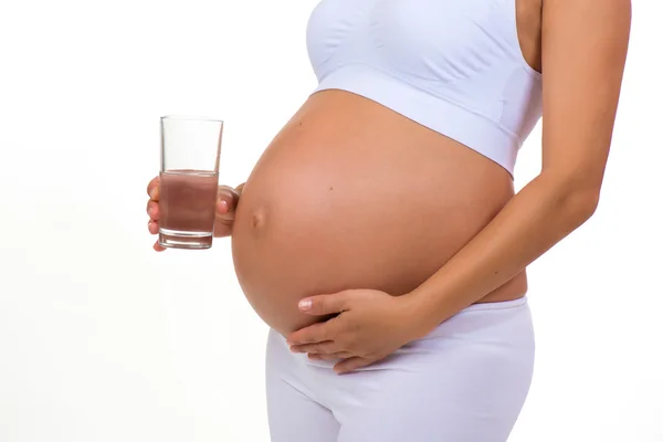 Close-up of belly of a pregnant woman and glass of water — Stock Photo, Image