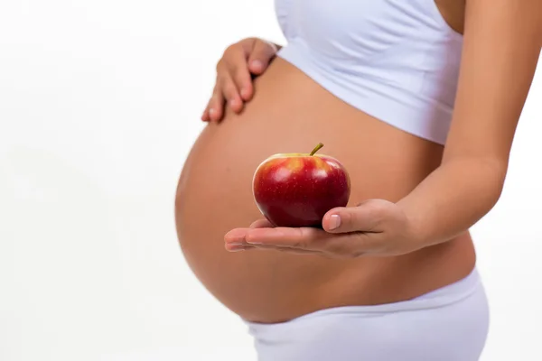 Close-up de barriga grávida e maçã. Vitaminas e alimentos saudáveis durante a gravidez — Fotografia de Stock