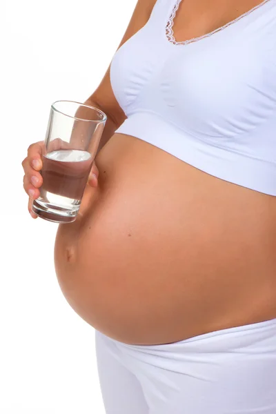 Έγκυος γυναίκα και ποτήρι νερό. Κάθετη φωτογραφία της κοιλιάς. Γκρο πλαν — Φωτογραφία Αρχείου