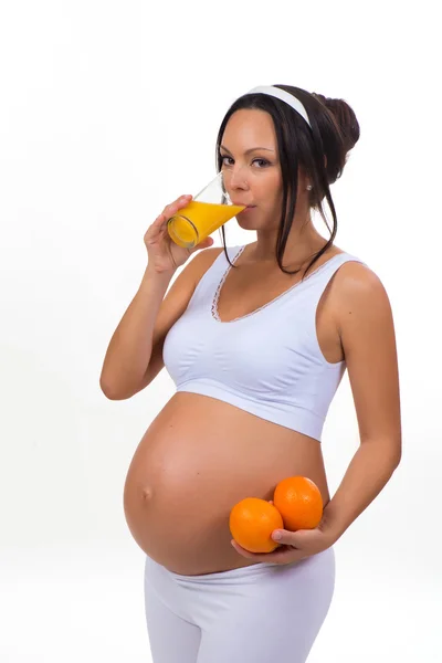 Pregnancy and vitamins. Pregnant woman and oranges and fresh juice. Isolated on white background — Stock Photo, Image