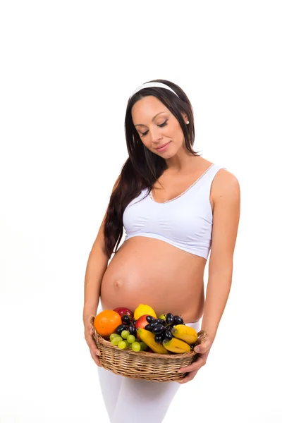 Mulher morena grávida bonita saudável com uma cesta de frutas. Menu de dieta durante a gravidez — Fotografia de Stock