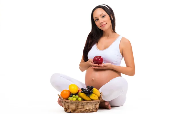 Witaminy i prawidłowe odżywianie w ciąży. Kobiety w ciąży z jabłkiem i kosz owoców — Zdjęcie stockowe