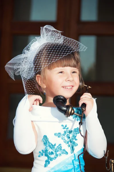 Retrato de uma menina em um chapéu com um véu e um telefone retro velho na mão — Fotografia de Stock