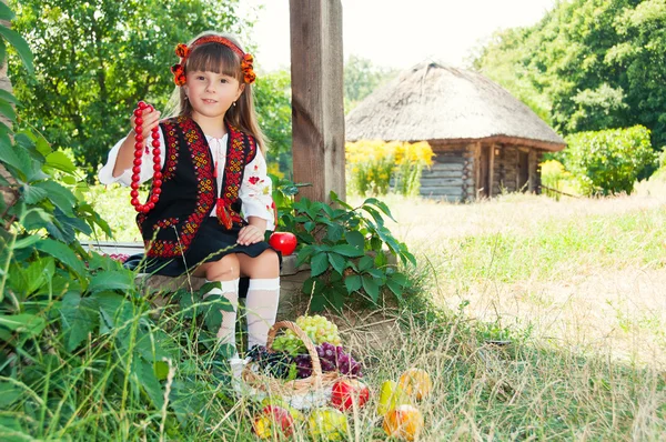 Ukrajinské vesnice. Dívka v národním huculské kostým sedí s ovocem — Stock fotografie