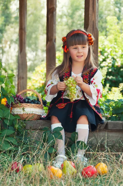 Dívka v tradičním kroji ukrajinská, posezení v zahradě s ovocem — Stock fotografie