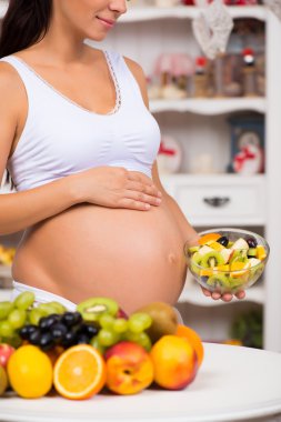 Taze meyve ve salata tabağı ile hamile bir karın close-up. Sağlıklı gebelik, diyet ve vitaminler