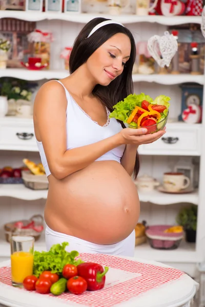 Mujer embarazada sonriente con un plato de ensalada de verduras frescas. Embarazo y alimentación saludable — Foto de Stock