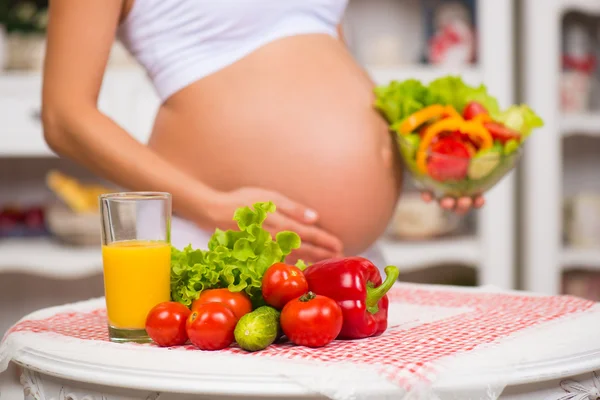 Close-up de uma barriga grávida. Saúde da Mulher, comida fortificada. Legumes frescos, dieta e figura — Fotografia de Stock