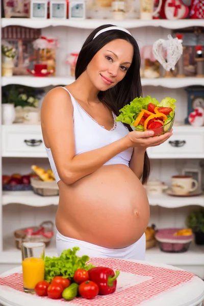 Smiling pregnant woman with a plate of fresh vegetable salad. Pregnancy and healthy food — Stock Photo, Image