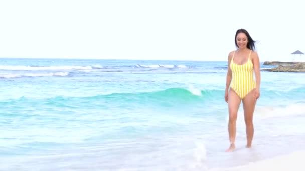 Mladá usměvavá krásná žena v plavkách kráčí podél mořského pobřeží. Letní dovolená u moře. Azurové vlny — Stock video