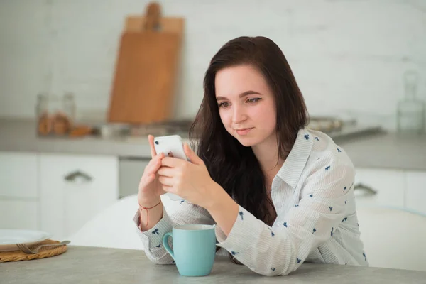 Young brunette woman student with mobile phone. Social networks, smartphones and modern gadgets as a means of communication and leisure activities — Stock Photo, Image