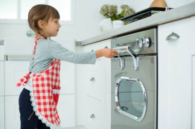 Küçük yardımcı. Mutfak önlüklü güzel bir kız pizza hazırlar, hamuru mutfaktaki fırına koyar..
