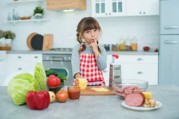 Little Cute Smiling Girl Pigtails Checkered Cooking Apron Rubs Cheese — Stock Photo, Image