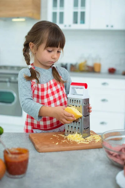 Little Cute Smiling Girl Pigtails Checkered Cooking Apron Rubs Cheese — Stock Photo, Image