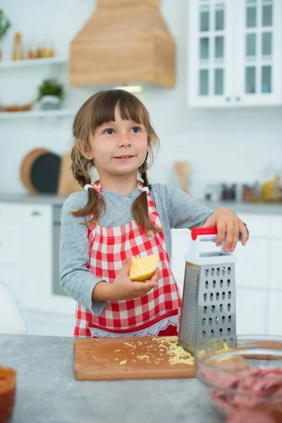 Little Cute Smiling Girl Pigtails Checkered Cooking Apron Rubs Cheese — Stock Photo, Image