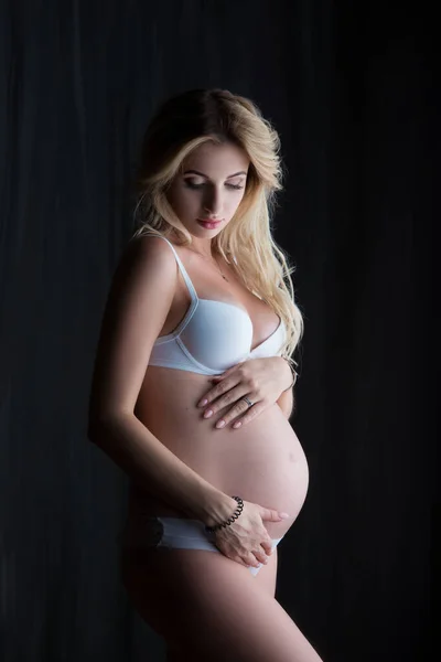 Beautiful Pregnant Blonde Woman Stands Hugs Her Tummy Black Background — Stock Photo, Image